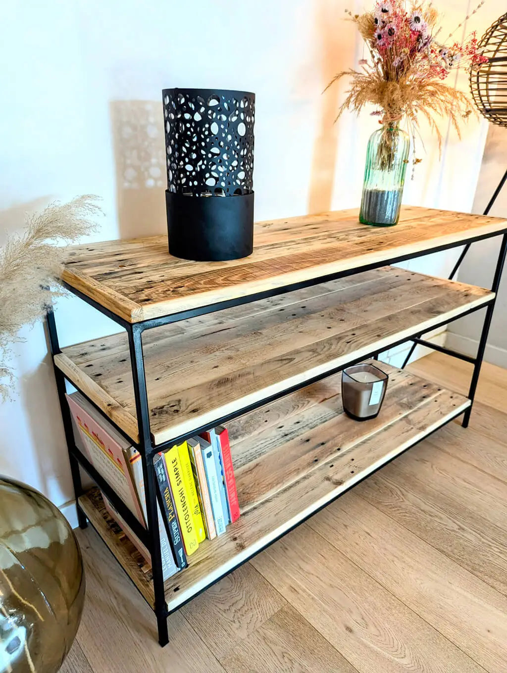 Étagère Louise en bois recyclé et métal noir, design industriel avec rangements ouverts, décorée de livres, vase en verre et bougie.