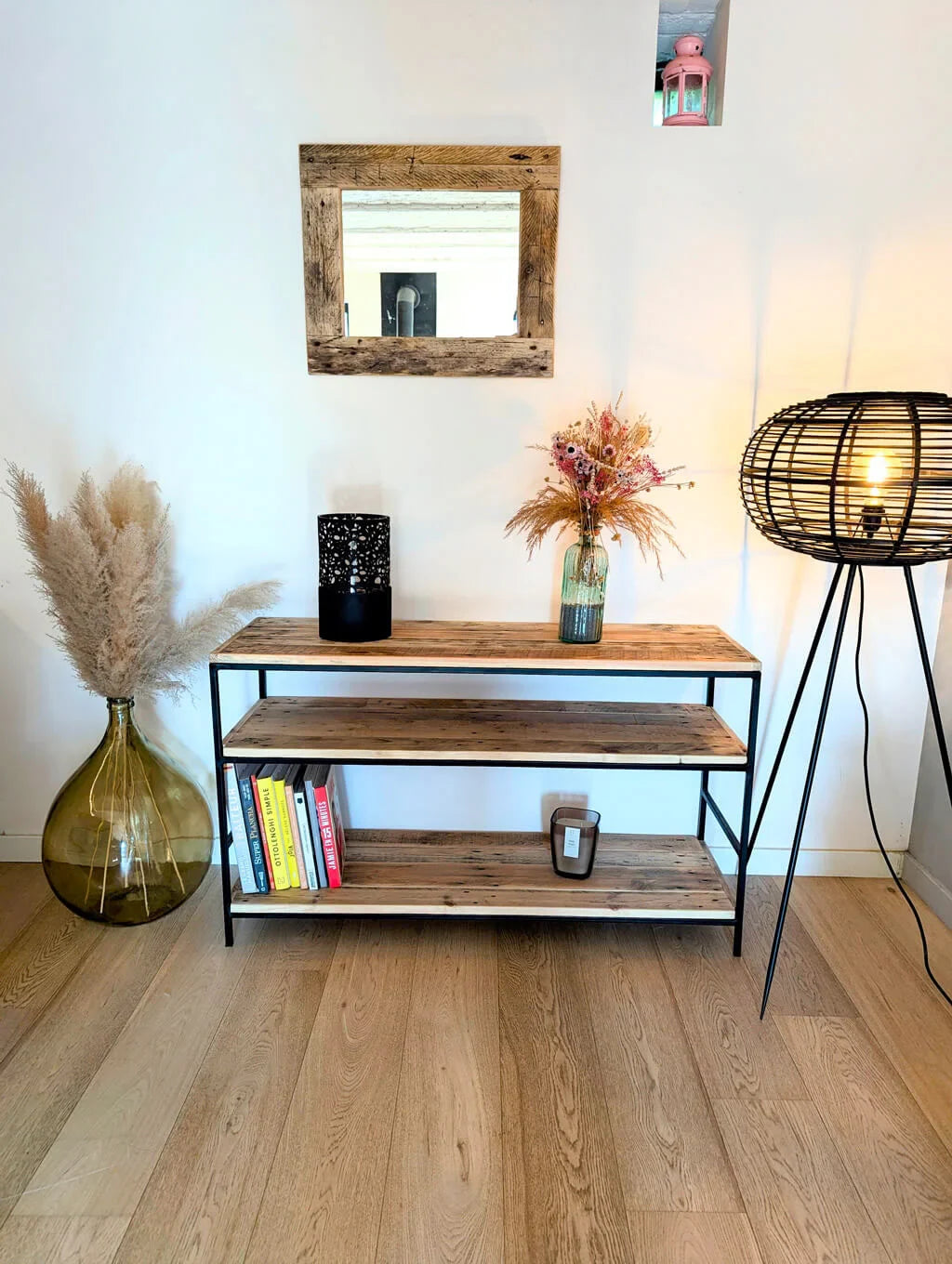 Étagère Louise en bois recyclé et métal noir, installée dans un intérieur lumineux avec miroir en bois, vase décoratif et lampe en rotin.